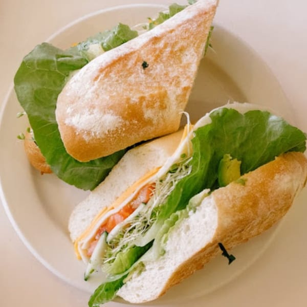 Two fresh Java Beach sandwiches on baguettes, filled with lettuce, cheese, tomatoes, and sprouts.