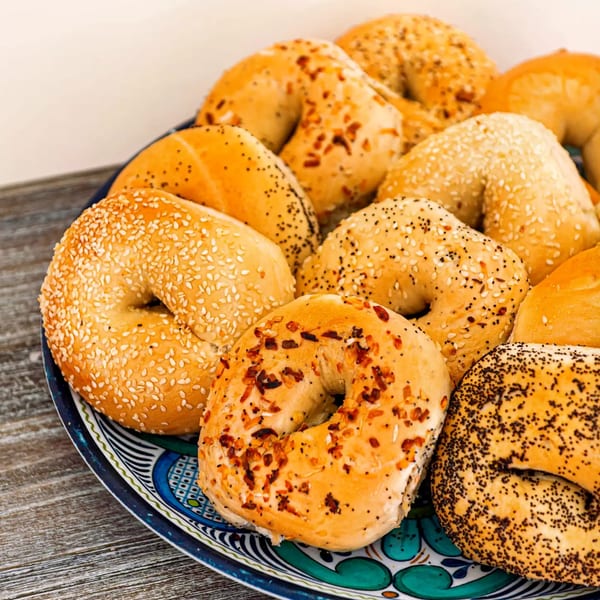 A colorful platter filled with various bagels, including sesame, poppy seed, and everything bagels.